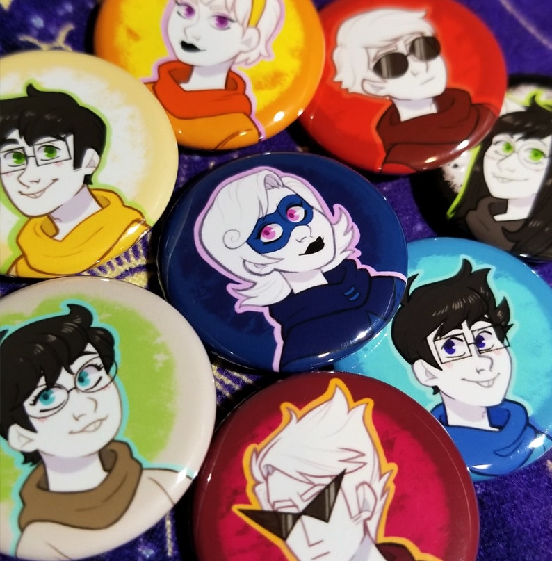 Puede incluir: Ocho botones redondos con fondos coloridos y personajes de dibujos animados. Los personajes llevan gafas, sombreros y m&aacute;scaras. Los botones son perfectos para a&ntilde;adir un toque de color a cualquier bolso, chaqueta o mochila.