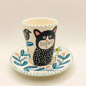 手作りの陶器製エスプレッソカップ。猫、黒い鳥、花のモチーフが手描きされています。カップとソーサー。手作りギフト。コーヒー愛好家へのギフト。