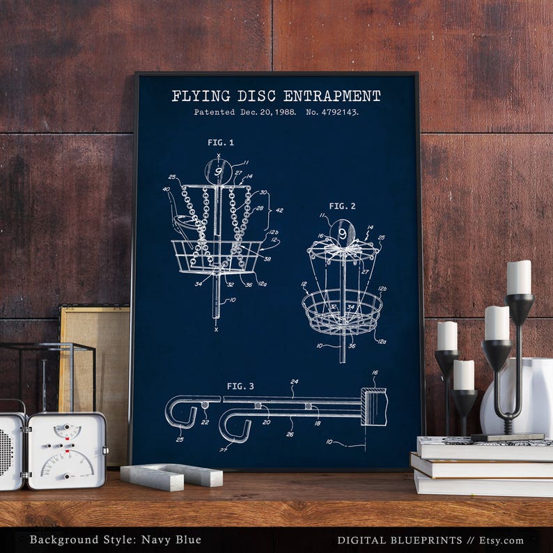 Może przedstawiać: Drukowany plakat w kolorze granatowym z vintage'owym rysunkiem patentowym urządzenia do łapania latającego dysku. Patent nosi tytuł "Flying Disc Entrapment" i został opatentowany 20 grudnia 1988 roku. Numer patentu to 4792143. Rysunek przedstawia trzy r&oacute;żne widoki urządzenia. Plakat jest idealny dla entuzjasty frisbee.