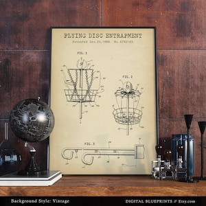 Może przedstawiać: Rysunek patentowy w stylu vintage dla urządzenia "Flying Disc Entrapment". Rysunek przedstawia trzy r&oacute;żne widoki urządzenia, kt&oacute;re jest koszem do frisbee. Patent został złożony 20 grudnia 1988 r., a numer patentu to 4792143.