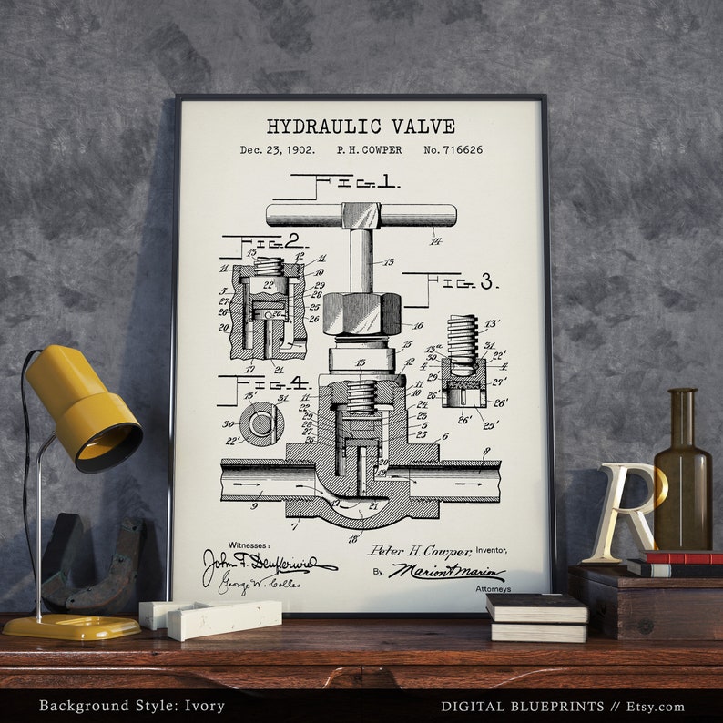 May include: A black and white vintage patent drawing of a hydraulic valve. The drawing is framed and displayed on a wooden surface with a yellow lamp and other decorative objects. The patent number is 716626 and the date is December 23, 1902.