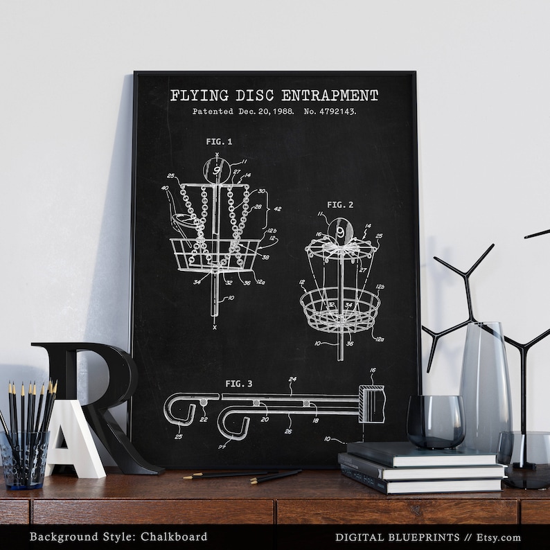 Może przedstawiać: Czarno-biała ilustracja rysunku patentowego pułapki na latający dysk na tle tablicy. Patent został złożony 20 grudnia 1988 roku, a numer patentu to 4792143. Rysunek przedstawia trzy r&oacute;żne widoki wynalazku.