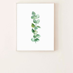 May include: A framed watercolor painting of a single sprig of eucalyptus leaves in shades of green against a white background.
