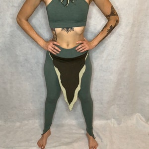 May include: A green halter top with a fringe detail and matching green leggings with a brown and cream triangle detail.
