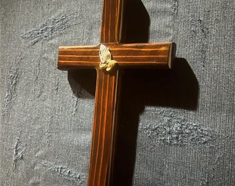 Cruz de pared de madera de secuoya con manos en oración y acabado en caoba.