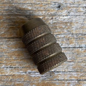 May include: A brass, knurled, cylindrical knob with a textured surface.