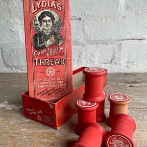May include: A vintage box of red Aunt Lydia's Carpet & Button Thread spools. The box features a portrait of a woman and the text "Aunt Lydia's Carpet & Button Thread". The spools are made of wood and have a red label with the text "Aunt Lydia's Carpet & Button Thread".