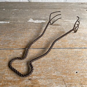 May include: Vintage, rusty, metal, twisted wire kitchen tongs with a heart-shaped handle.