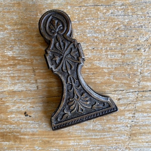 May include: A vintage metal paper clip with an ornate design. The clip is made of dark metal with a detailed floral pattern.