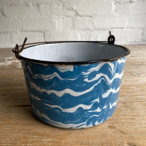 May include: A blue and white enamelware bucket with a black rim and a wire handle. The bucket has a marbled pattern.