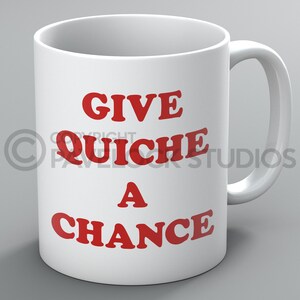 May include: White ceramic coffee mug with red text that reads "Give Quiche a Chance".