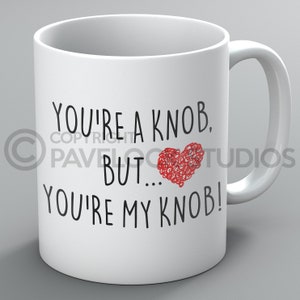 May include: White ceramic mug with black text that reads "You're a knob, but... you're my knob!" with a red heart in the middle.