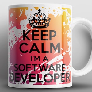 Può includere: Tazza in ceramica bianca con un design a splatter colorato. La tazza presenta una corona nera e il testo "Keep Calm I'm a Software Developer".