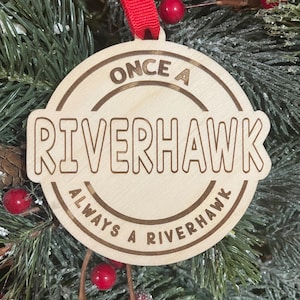 May include: A wooden Christmas ornament with the text "Once a Riverhawk Always a Riverhawk" in a circular design.