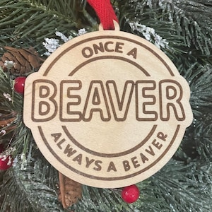 May include: A wooden Christmas ornament with the text "Once a Beaver Always a Beaver" in a circular design.