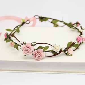 May include: A delicate floral crown with pink and white flowers woven into a brown vine base.