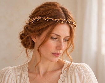 May include: A gold-toned hair vine featuring a delicate, flexible wire structure adorned with small, uniform teardrop-shaped beads. The accessory is worn across the crown of the head, resting above the forehead, and is crafted from metallic gold wire.