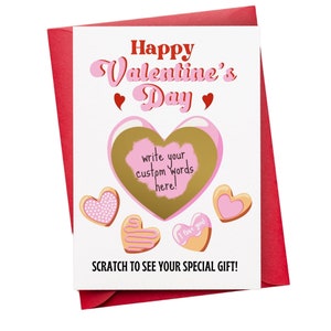 May include: A Valentine's Day card with a gold heart that can be scratched to reveal a hidden message. The card has a pink and white design with the words "Happy Valentine's Day" and "Scratch to see your special gift!"