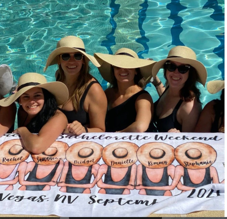 May include: A white beach towel with a bachelorette weekend theme. The towel features a group of women wearing black swimsuits and large straw hats. The text on the towel reads "Bachelorette Weekend", "Vegas, NV September 2021", and the names "Rachel", "Samantha", "Bridget", "Danielle", "Kimmy", and "Stephanie".