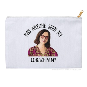May include: White canvas zippered pouch with a graphic of a woman with brown hair and glasses. The text "Has anyone seen my Lorazepam?" is printed in black on the pouch.