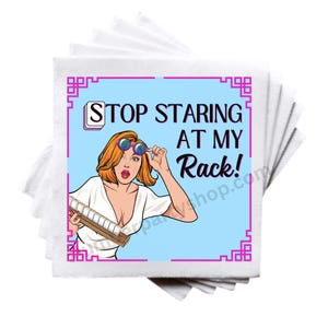 Op de afbeelding: Een stapel witte papieren servetten met een pop-art ontwerp. Het ontwerp toont een vrouw met oranje haar en een zonnebril, die een Scrabble-rek vasthoudt. De tekst op het ontwerp luidt "STOP STARING AT MY Rack!"