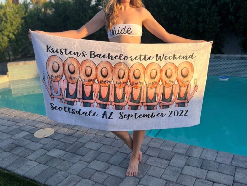 May include: White beach towel with a personalized design featuring a group of women in black swimsuits and straw hats. The text on the towel reads "Kristen's Bachelorette Weekend, Scottsdale, AZ September 2022".
