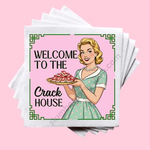 May include: A stack of white paper napkins with a pink square featuring a retro illustration. The illustration shows a woman in a green dress holding a tray of red objects, with the text "WELCOME TO THE CRACK HOUSE" in black.