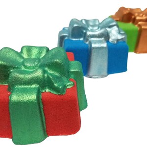 K&ouml;nnte beinhalten: Drei badebomben in Geschenkform in Rot, Blau und Gr&uuml;n. Jede Badebombe hat eine gr&uuml;ne Schleife oben drauf.