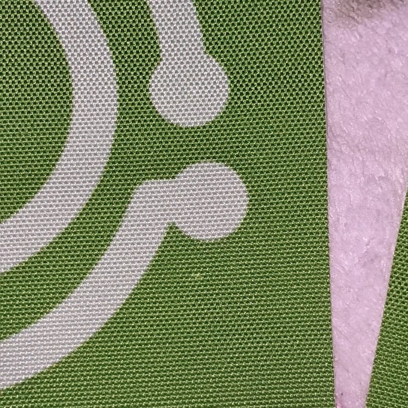 May include: Green fabric with a white pattern of two overlapping circles. The fabric has a textured, woven appearance.
