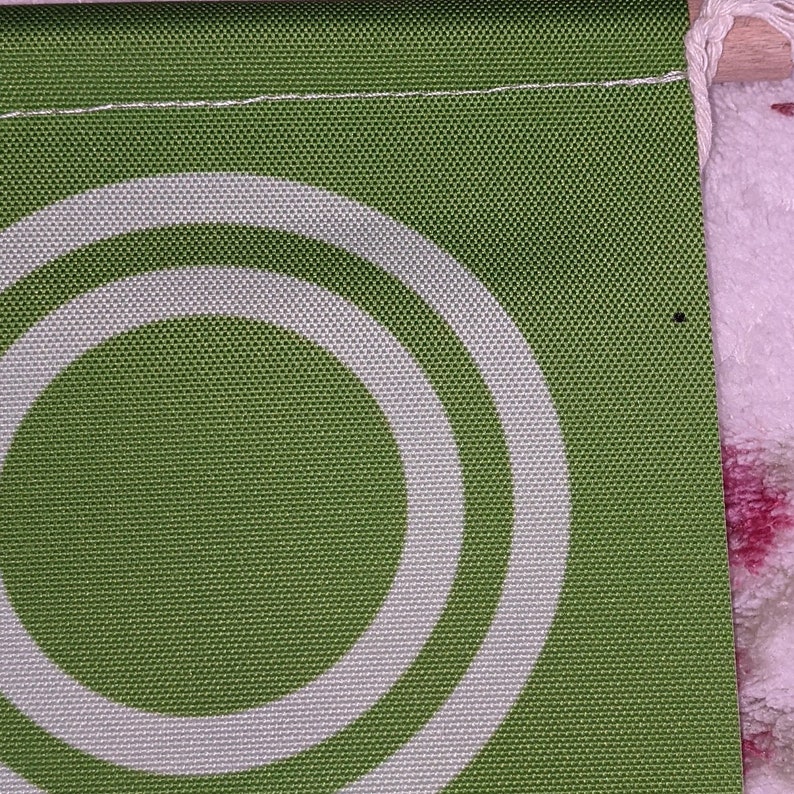 May include: Green fabric with two white concentric circles. The fabric has a textured woven pattern.
