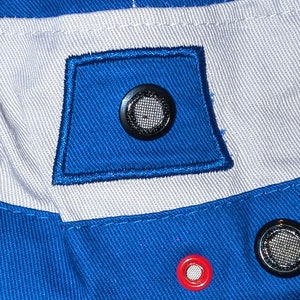 May include: Close-up of a blue and white fabric with a black mesh vent and a red grommet. The fabric has a woven texture.