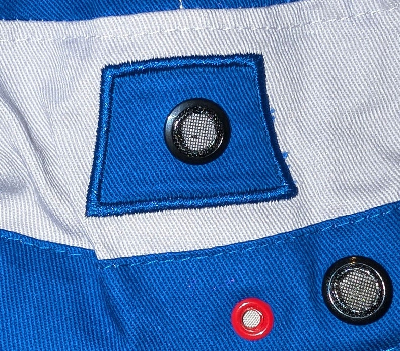 May include: Close-up of a blue and white fabric with a black mesh vent and a red grommet. The fabric has a woven texture.
