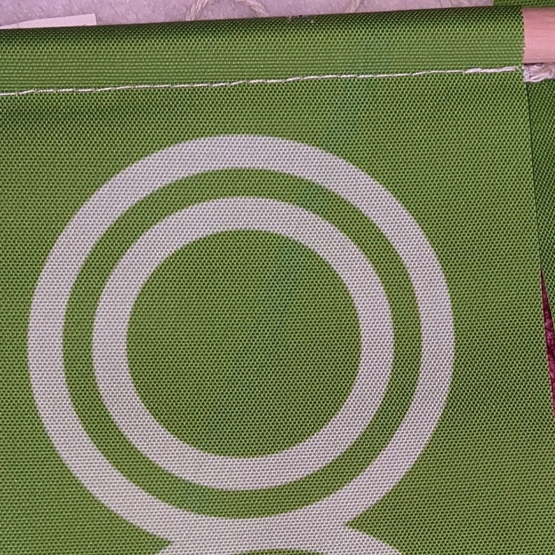 May include: Green fabric with a white double circle design. The fabric has a textured woven appearance.