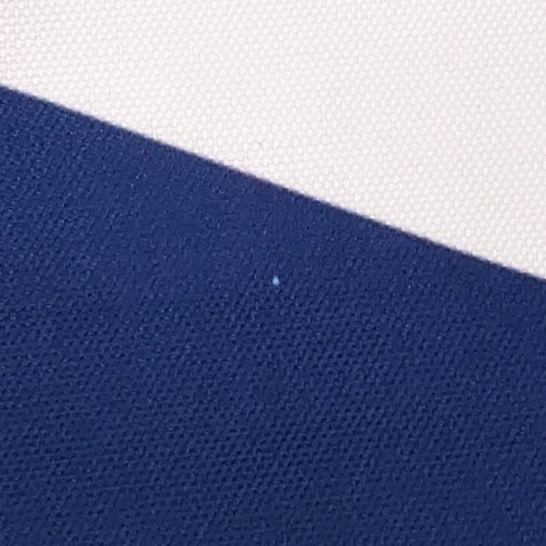 May include: A close-up of a blue fabric with a white fabric diagonal to it.
