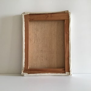 K&ouml;nnte beinhalten: Die R&uuml;ckseite einer rechteckigen Leinwand, die auf einen Holzrahmen gespannt ist. Die hellbraune, strukturierte Leinwand ist mit umgeschlagenen Kanten an den vier Holzleisten befestigt. Der Holzrahmen zeigt eine nat&uuml;rliche Maserung.
