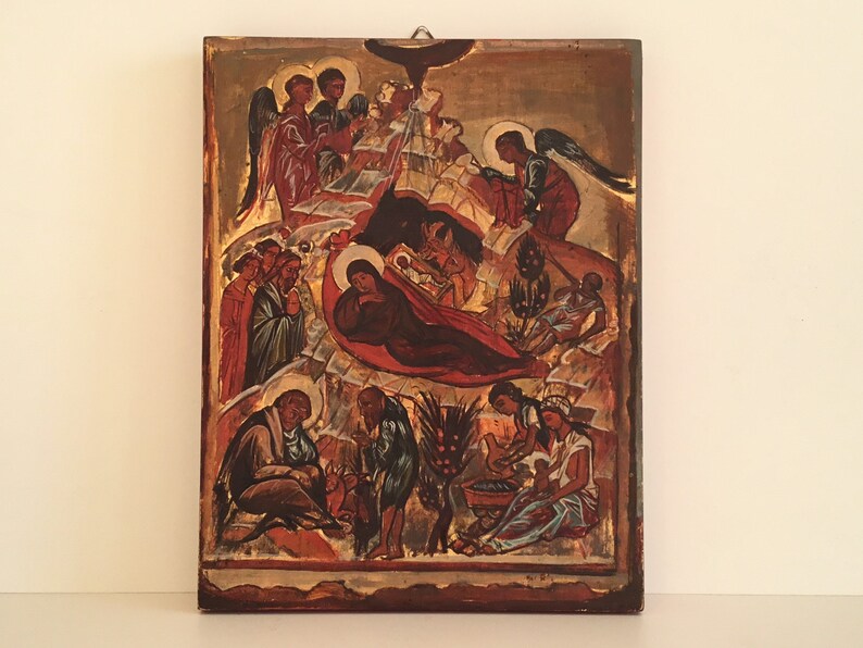 May include: A vintage religious icon depicting the Nativity scene. The artwork features figures in red, brown, and gold tones, with angels and other biblical figures. The icon is mounted on a wooden panel with a gold border.