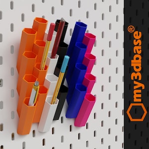 Puede incluir: Un conjunto de cuatro organizadores hexagonales para tablero de clavijas en naranja, blanco, azul y rosa. Los organizadores est&aacute;n llenos de bol&iacute;grafos, l&aacute;pices y rotuladores. El tablero de clavijas es blanco con agujeros espaciados uniformemente. El texto "my3dbase&reg;" es visible en la esquina superior derecha de la imagen.