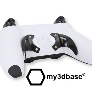 以下が含まれることがあります： 黒色のグリップと背面パドルが付いた白いビデオゲームコントローラー。コントローラーには、下部に「my3dbase」というテキストが書かれた黒い六角形のロゴがあります。