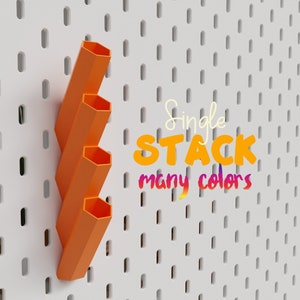 Puede incluir: Una pila de cuatro organizadores hexagonales de tablero de clavijas naranja. Los organizadores est&aacute;n apilados uno encima del otro y est&aacute;n montados en un tablero de clavijas blanco. El texto "Single STACK many colors" est&aacute; escrito en colores arco&iacute;ris en el tablero de clavijas.