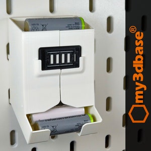 Könnte beinhalten: Weißer Batterie-Aufbewahrungsorganisator aus Kunststoff mit zwei Fächern für AA-Batterien. Der Organizer hat ein schwarzes Etikett mit dem Text "Ni-MH" darauf. Der Organizer ist für die Montage an einer Lochwand konzipiert.