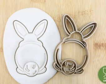 May include: A brown plastic cookie cutter shaped like a bunny rabbit with a rounded body and long ears. The cutter is designed to cut out bunny shapes from cookie dough.