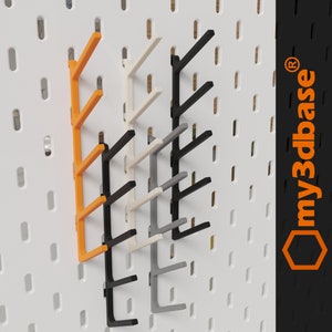 Könnte beinhalten: Ein Satz von fünf Steckbrett-Haken in verschiedenen Farben, darunter Orange, Weiß, Grau und Schwarz. Die Haken sind für die Verwendung an einer Steckbrett-Wand konzipiert.