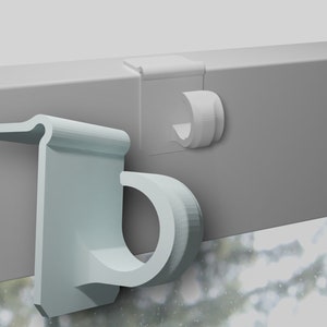 May include: Two white plastic hooks for hanging curtains or blinds. The hooks are designed to be attached to a window frame.