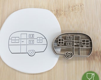 May include: A wooden cookie cutter in the shape of a vintage camper. The cutter is food grade and has a brown color.
