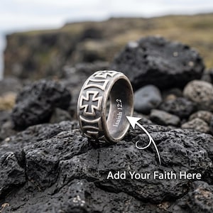 Könnte beinhalten: Ein silberfarbener Metallring mit einem sich wiederholenden Kreuzmuster auf dem äußeren Band. Die Innenseite des Rings ist mit dem Text Isaiah 12:2 graviert. Ein weißer Pfeil zeigt auf den Innentext nahe dem Satz Add Your Faith Here.