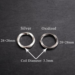May include: Two silver rings, one polished and one oxidized, each measuring 28x28mm. The coil diameter is 3.3mm. The rings are displayed on a dark gray surface, with text labels indicating their finish.