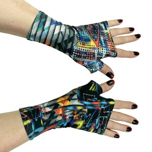 Könnte beinhalten: Ein Paar fingerlose Handschuhe mit einem lebendigen, mehrfarbigen geometrischen Muster. Der Stoff zeigt ein komplexes Design aus Punkten, Linien und abstrakten Formen in Blau-, Gelb-, Rot- und Schwarztönen, das den Handgelenk- und Handbereich bedeckt.