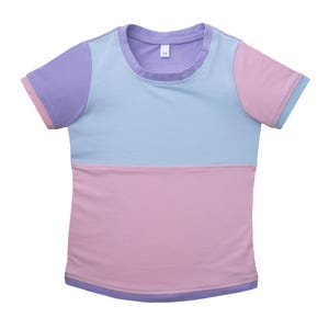 Könnte beinhalten: Ein pastellfarbenes T-Shirt mit Colorblock-Design. Der obere Bereich ist hellblau, die Ärmel sind lavendelfarben mit rosa Besatz und der untere Bereich ist rosa. Der Halsausschnitt und der Saum sind mit Lavendel verziert.