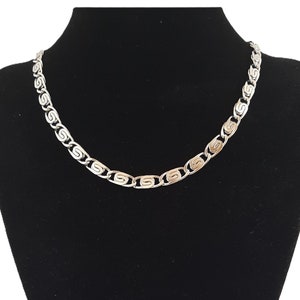 May include: A silver chain necklace with a patterned link design.