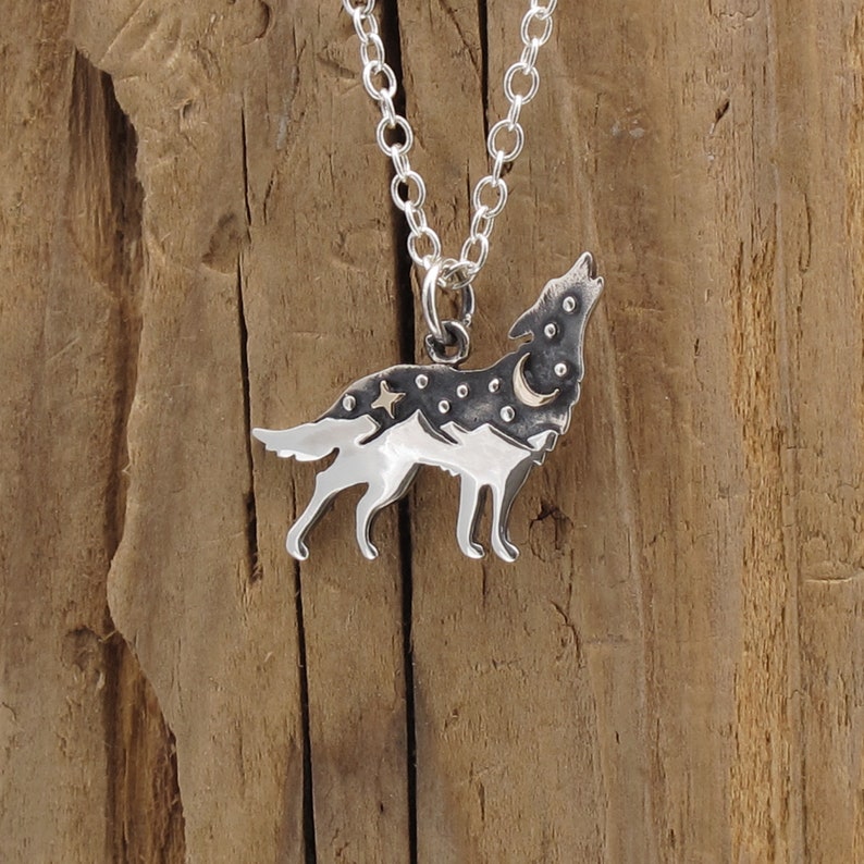 K&ouml;nnte beinhalten: Eine silberne Halskette mit einem Wolf-Anh&auml;nger. Der Wolf heult zum Mond und hat ein sternenklaren Nachthimmel-Design. Der Anh&auml;nger ist aus Sterlingsilber gefertigt und ein wundersch&ouml;nes Schmuckst&uuml;ck.